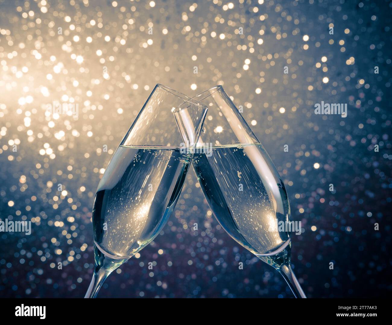 Due flauti champagne con bolle d'oro rendono cheers sulla luce blu sfondo bokeh di fondo con spazio per il testo Foto Stock