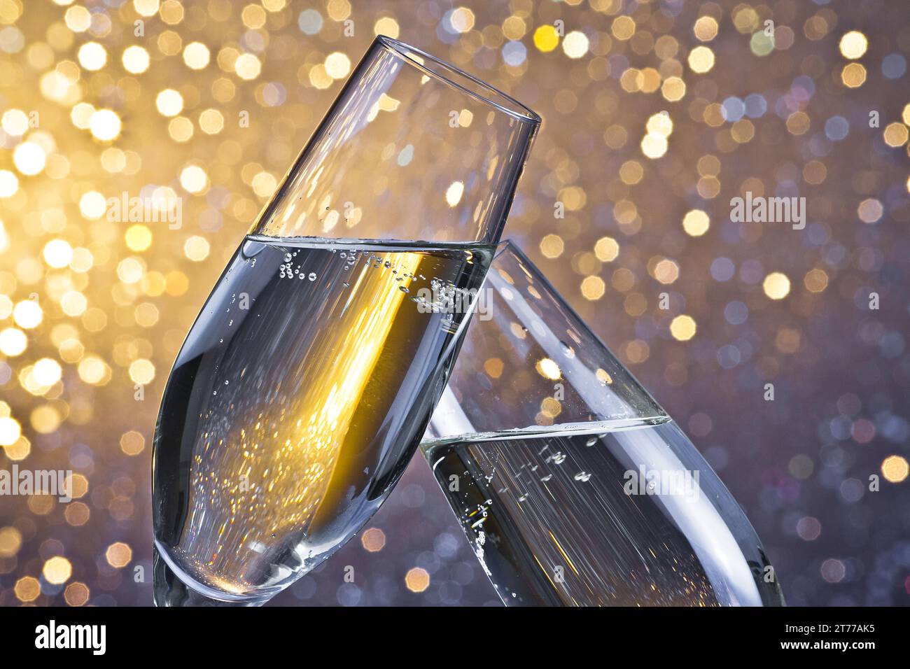 un paio di flauti di champagne con bolle d'oro fanno il tifo su uno sfondo bokeh leggero Foto Stock