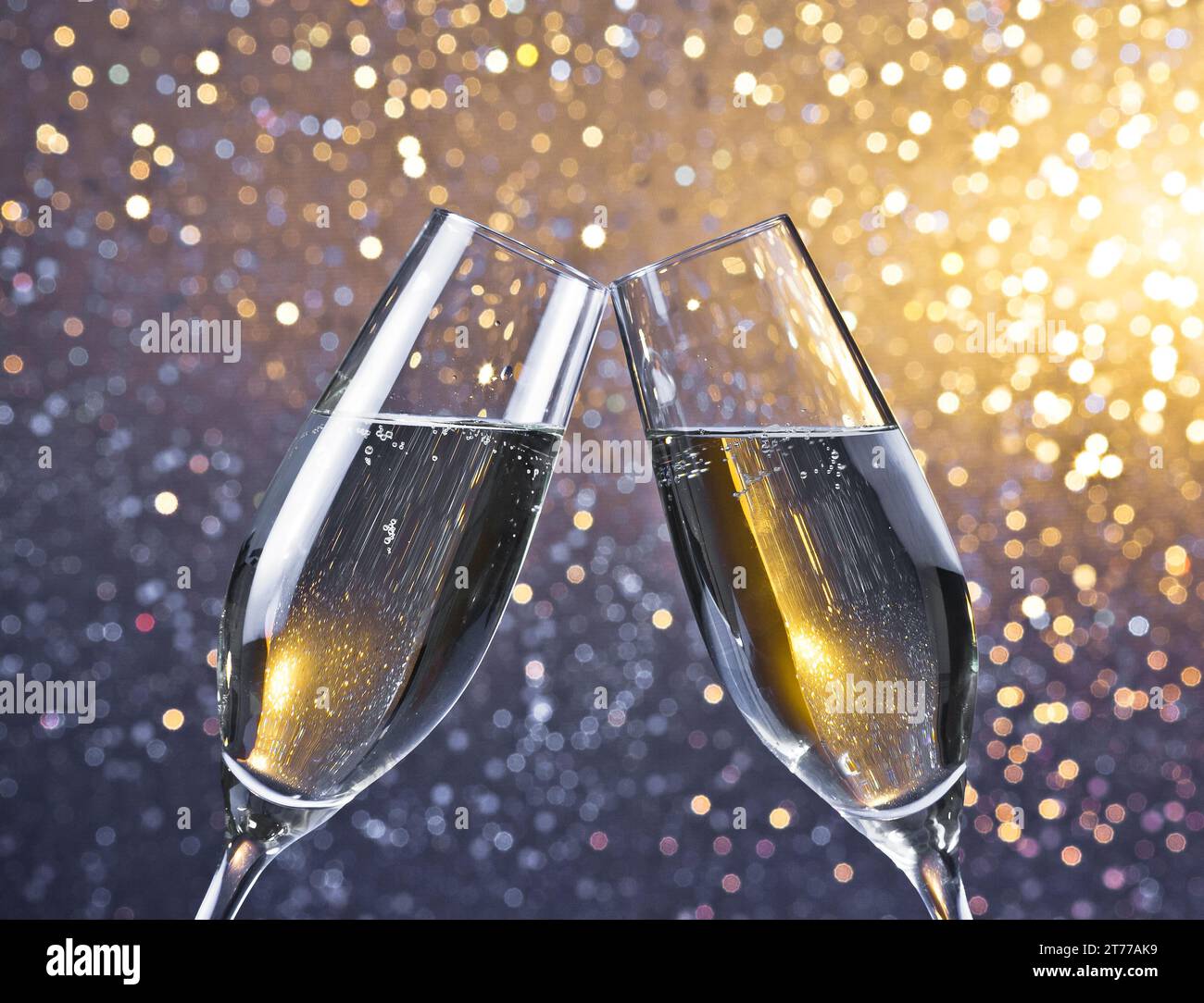 dettaglio di due flauti di champagne con bolle d'oro che fanno il tifo su uno sfondo bokeh leggero con spazio per il testo Foto Stock
