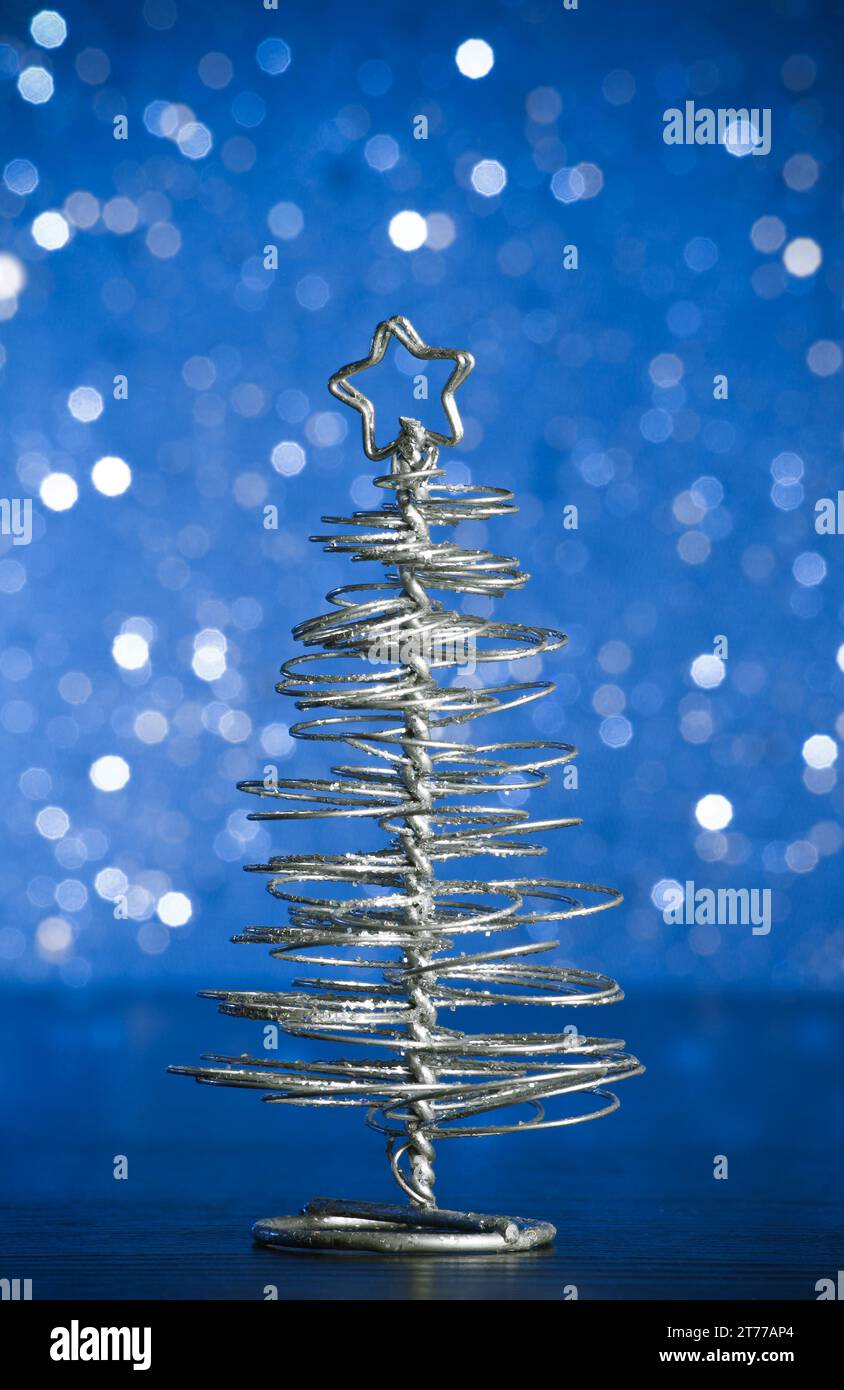 primo piano del moderno albero di natale metallizzato su un tavolo in legno su sfondo bokeh chiaro e blu Foto Stock