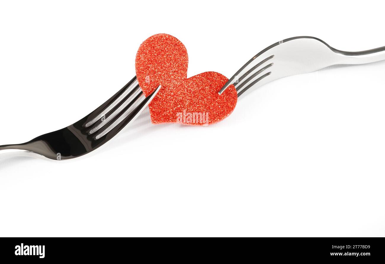 dettaglio con cuore rosso decorativo vicino alle forchette su sfondo bianco con spazio per il testo, cena di san valentino concettuale Foto Stock