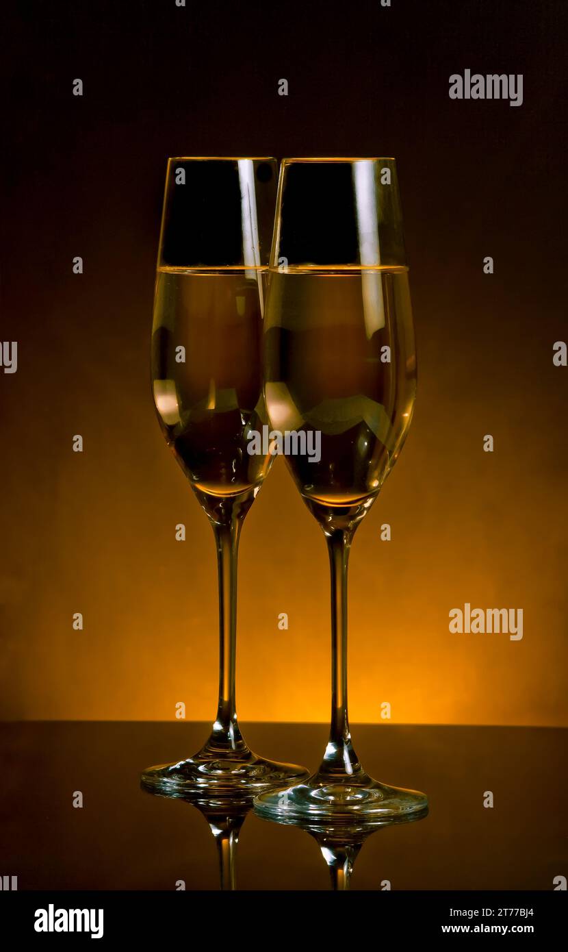 un paio di flute di champagne su sfondo chiaro dorato scuro con spazio per il testo Foto Stock
