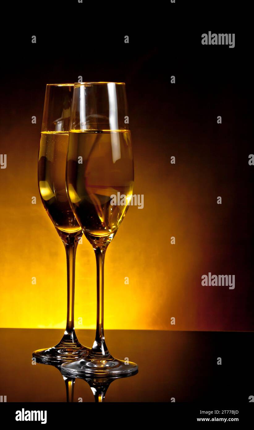 un paio di flute di champagne sul tavolo su sfondo chiaro dorato scuro con spazio per il testo Foto Stock
