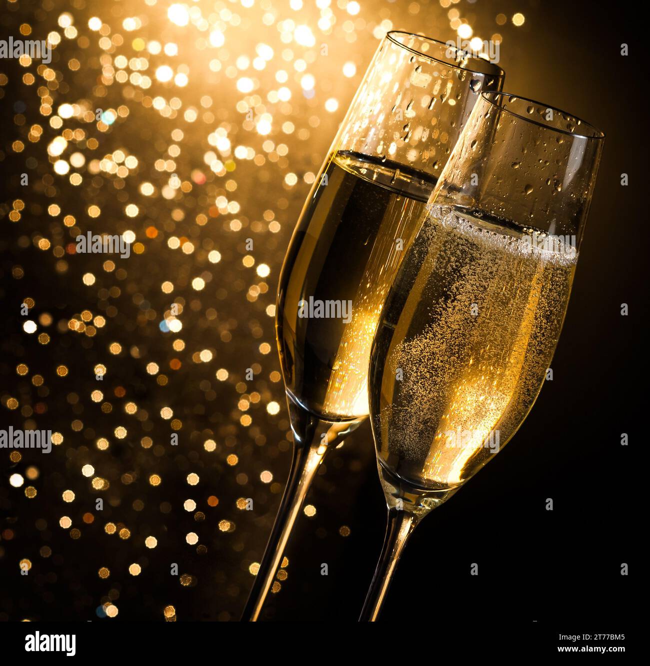 flauti di champagne con bollicine dorate su sfondo bokeh chiaro dorato scuro con spazio per il testo Foto Stock