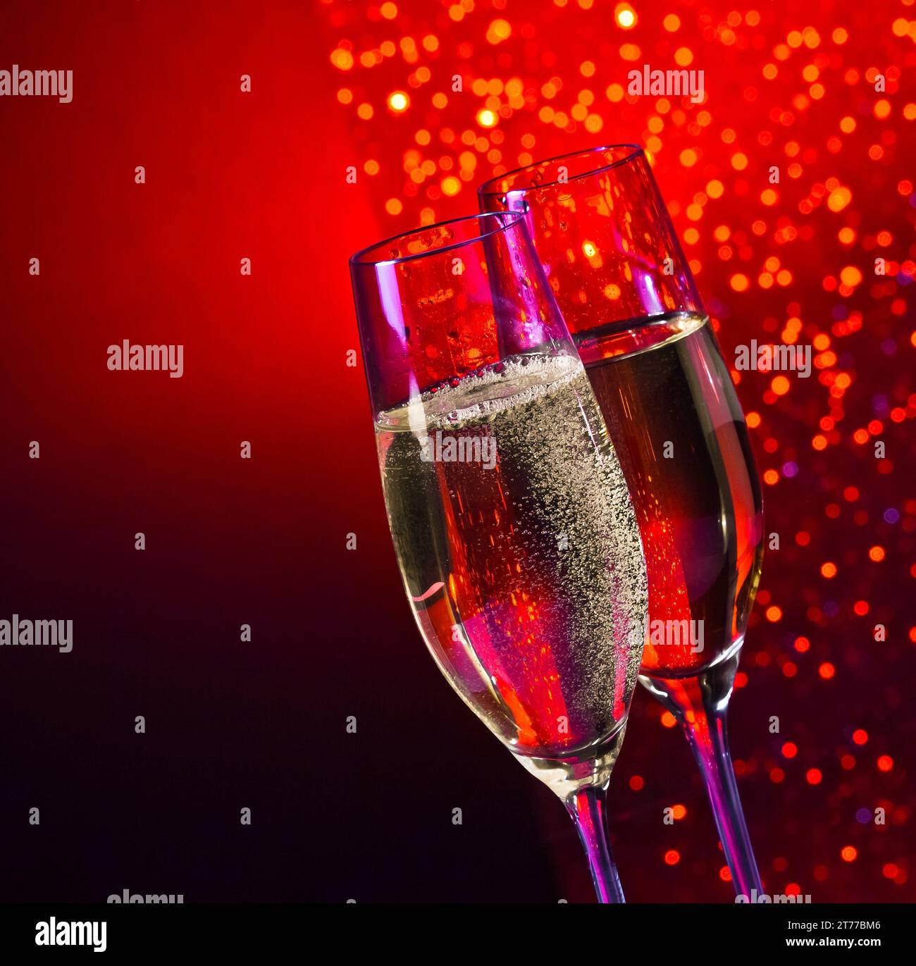 flauti di champagne con bollicine dorate su sfondo bokeh rosso scuro e viola chiaro con spazio per il testo Foto Stock