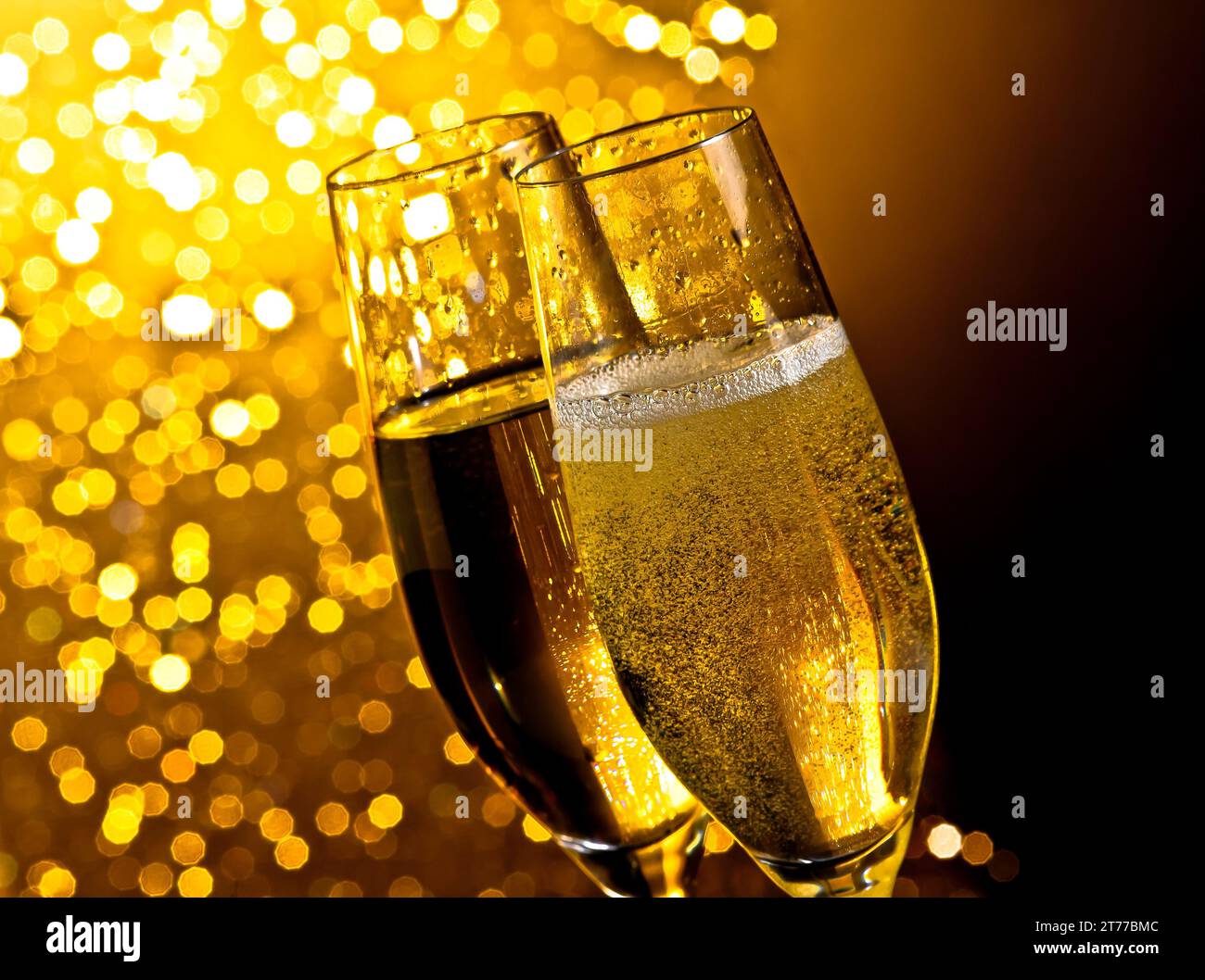 dettaglio di flauti di champagne con bolle dorate su sfondo bokeh chiaro dorato scuro con spazio per il testo Foto Stock