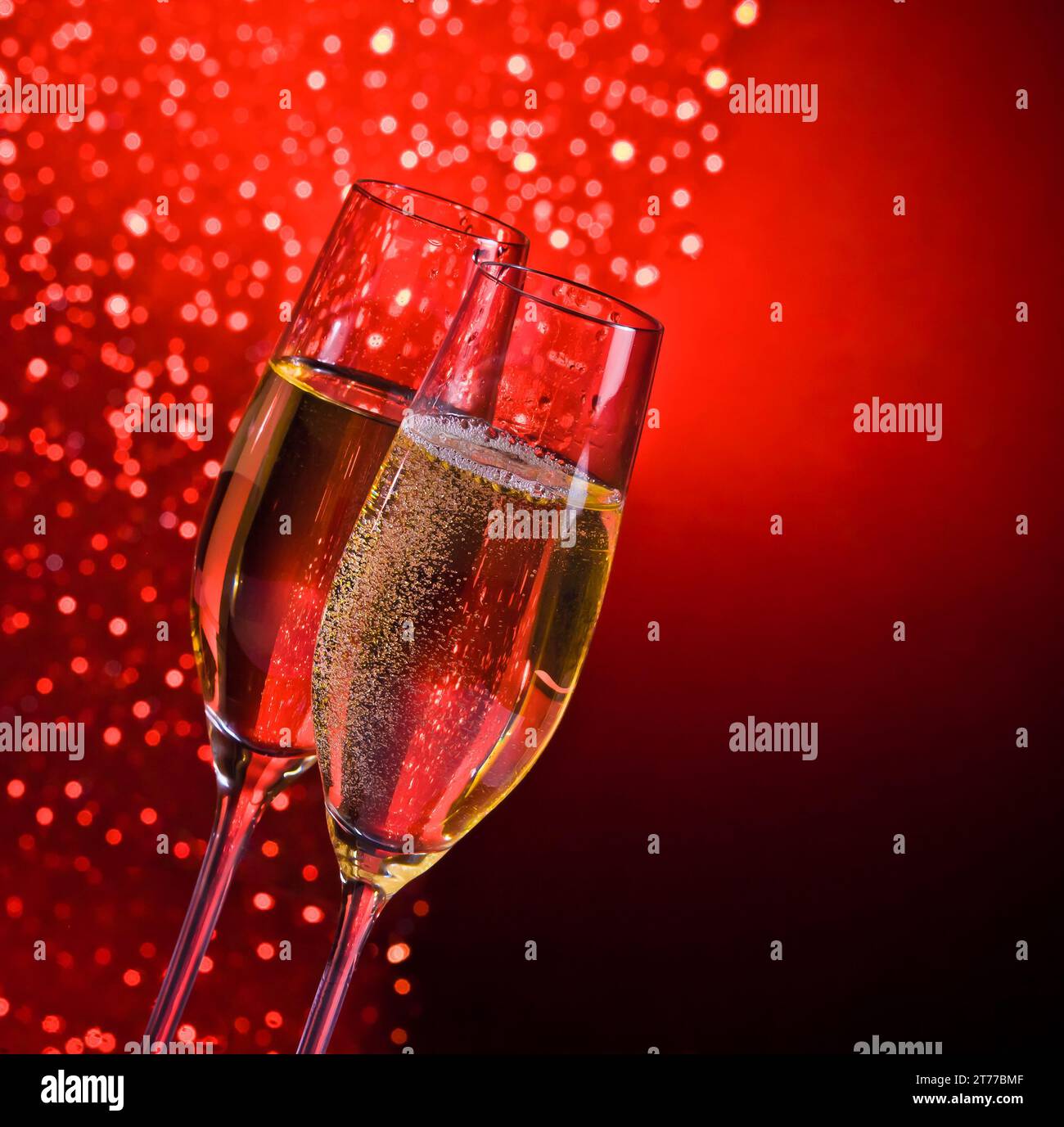flauti di champagne con bolle dorate su sfondo bokeh chiaro rosso scuro con spazio per il testo Foto Stock