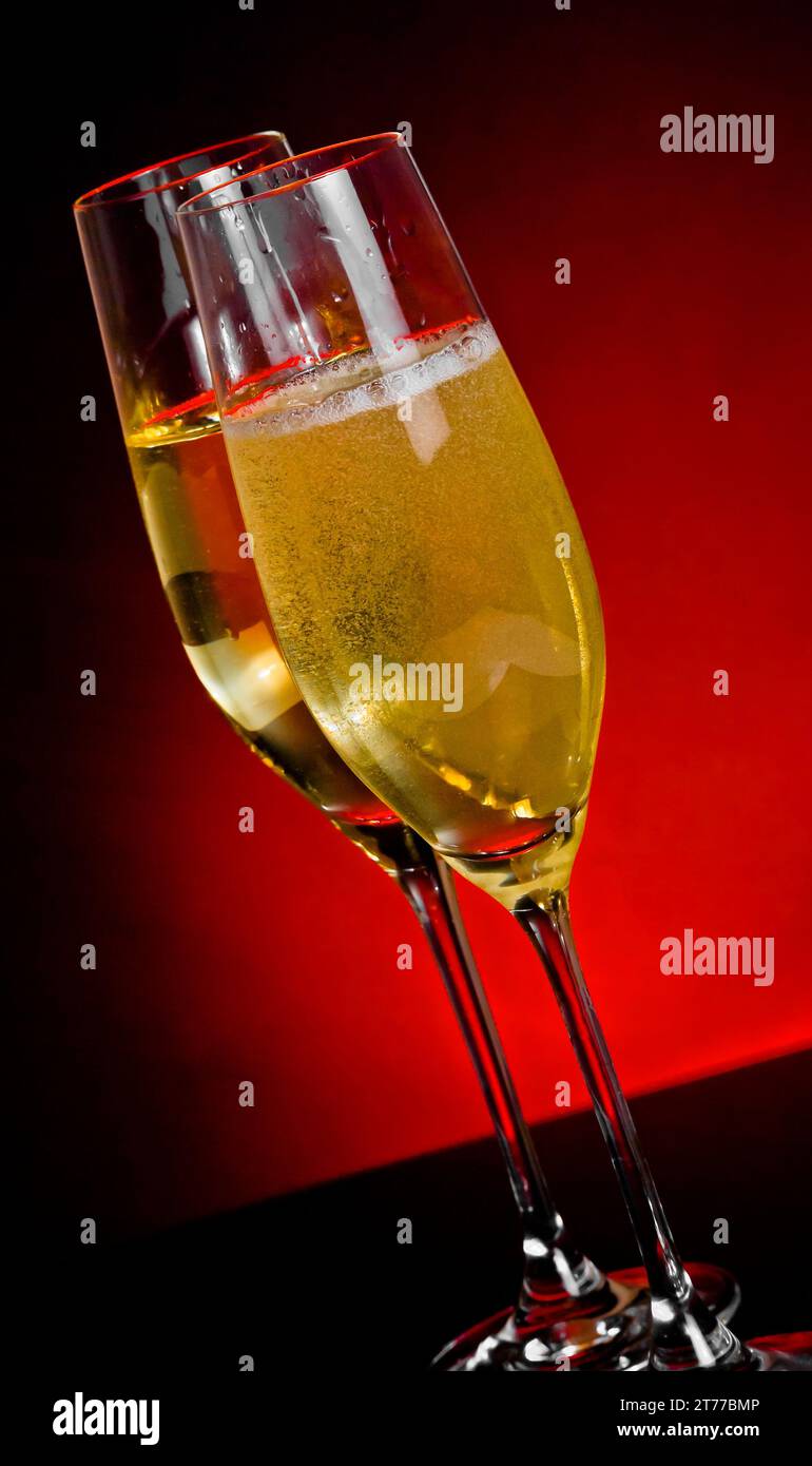 flute di champagne con bolle dorate su sfondo rosso scuro chiaro con spazio per il testo Foto Stock