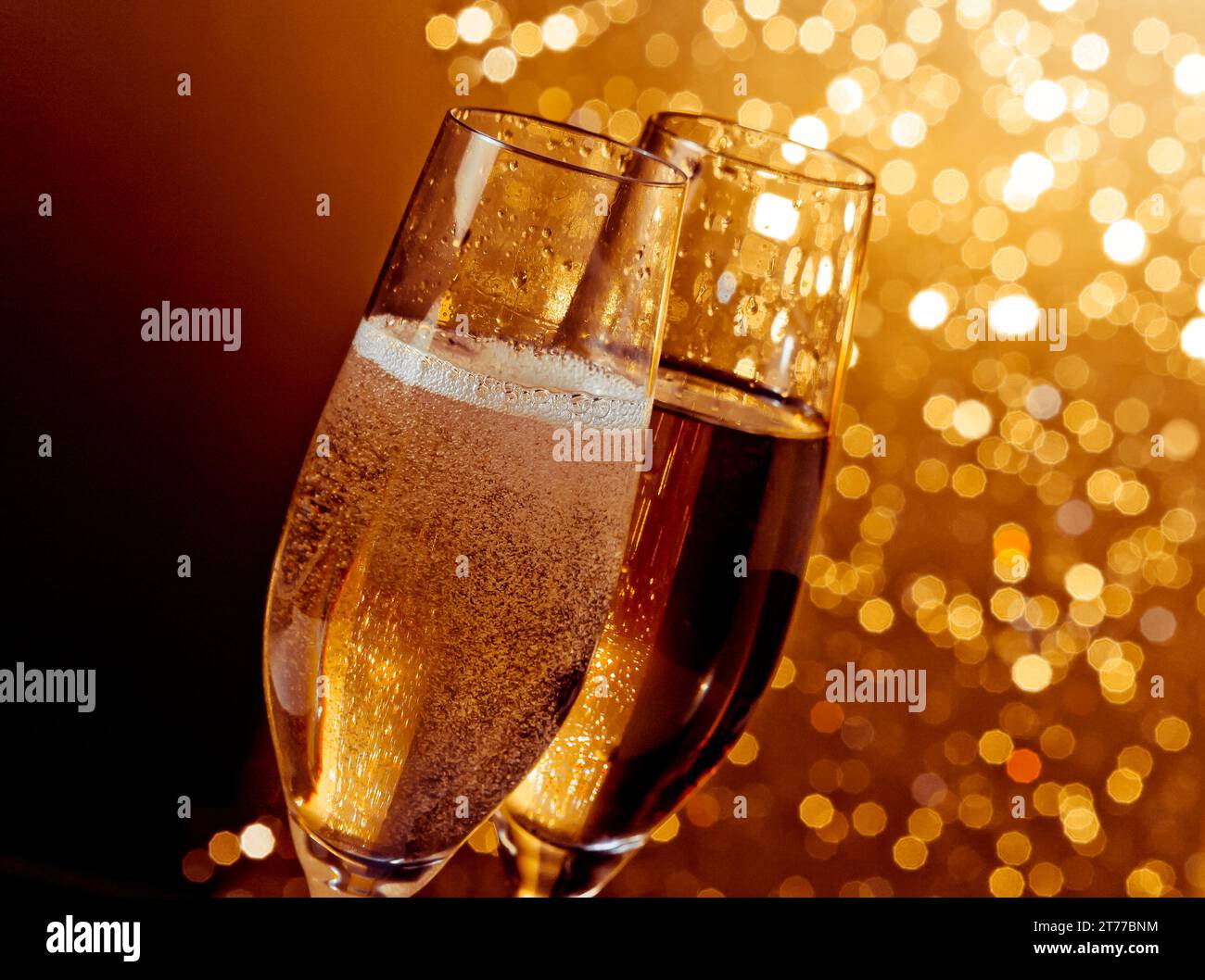 dettaglio di flauti di champagne con bolle dorate su sfondo bokeh caldo e chiaro con spazio per il testo Foto Stock