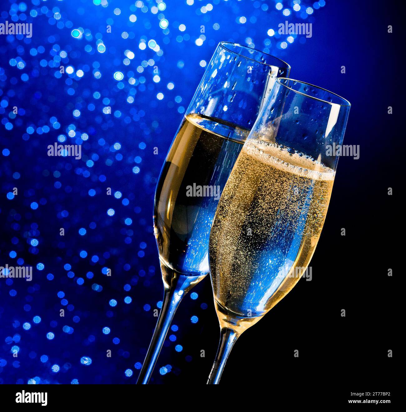 flauti di champagne con bolle dorate su sfondo bokeh chiaro blu scuro con spazio per il testo Foto Stock
