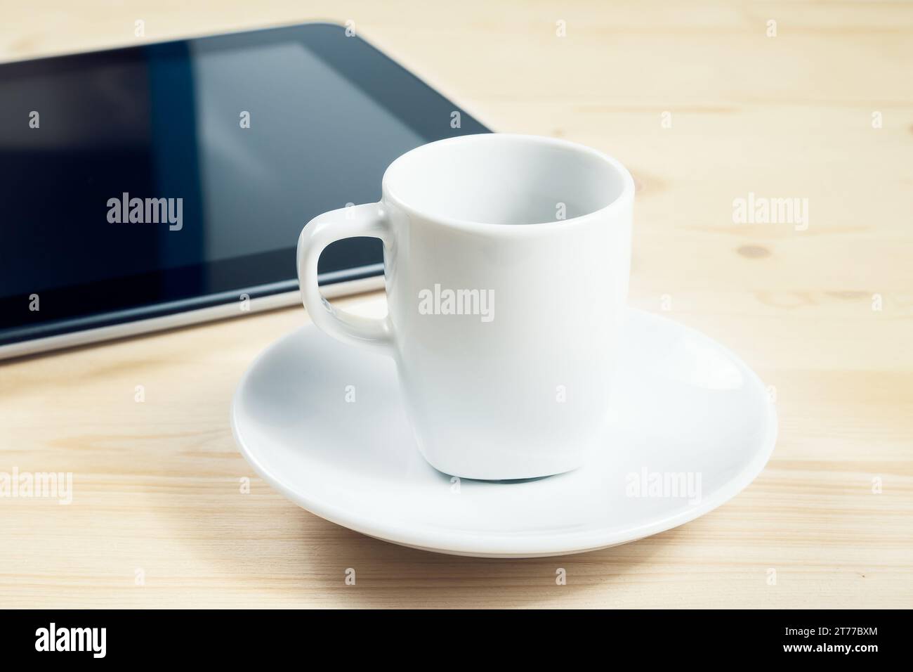 tazza di caffè davanti al tablet su un tavolo di legno, concetto di nuova tecnologia Foto Stock