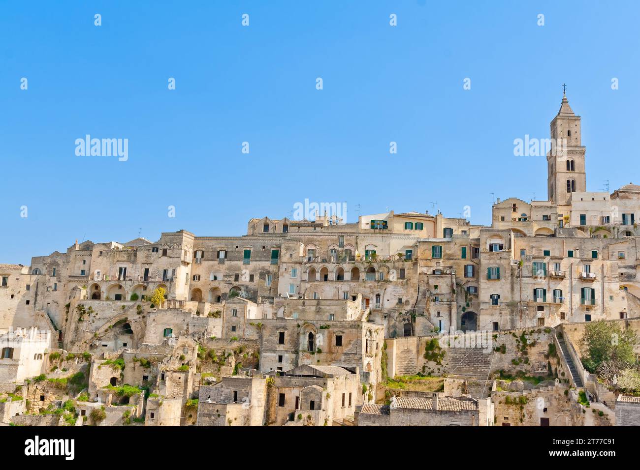 Vista panoramica delle pietre tipiche e della chiesa di Matera sotto il cielo blu. Basilicata, Italia Foto Stock