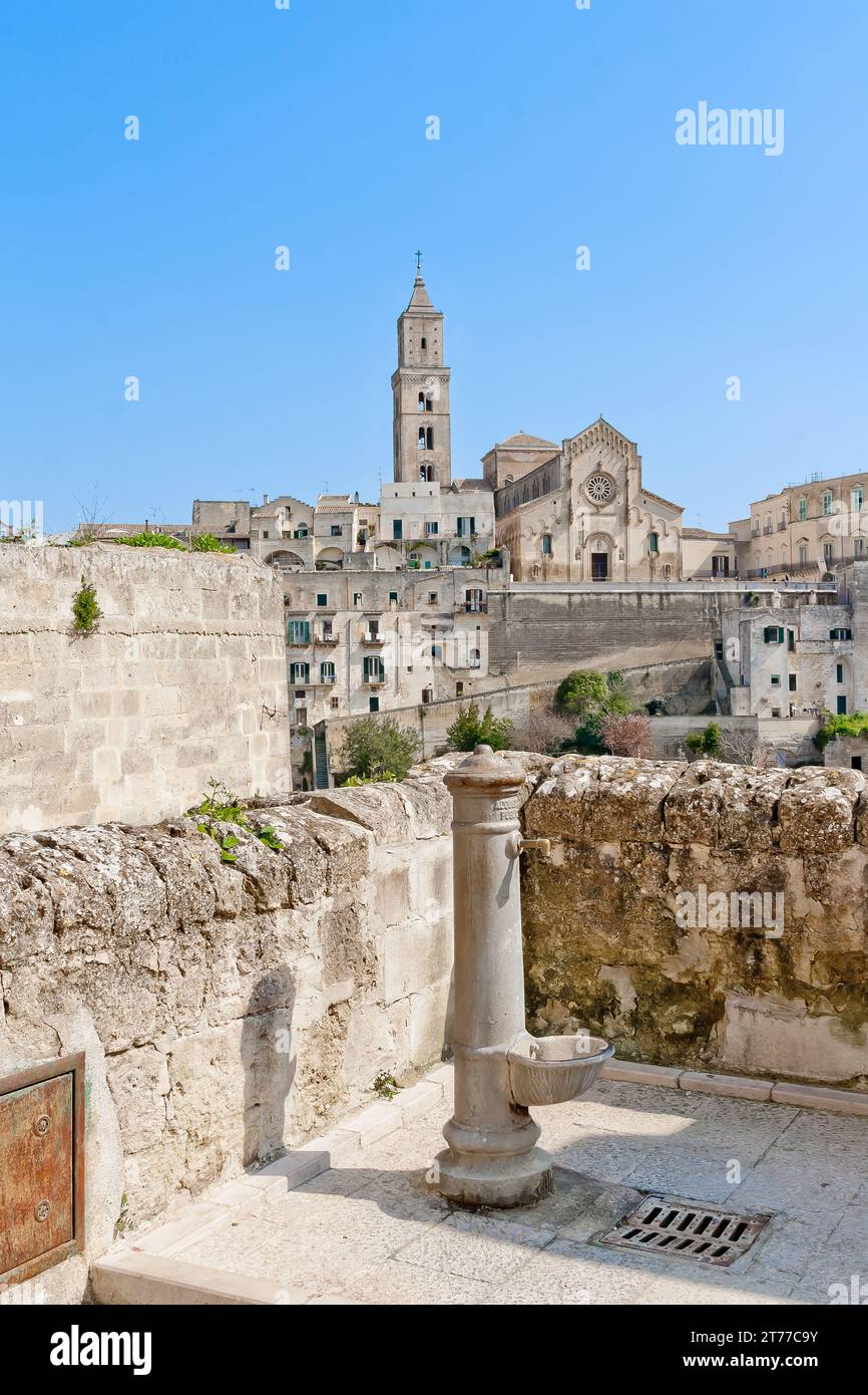 Vista panoramica del tipico erogatore d'acqua e della chiesa di Matera sotto il cielo blu. Basilicata, Italia Foto Stock