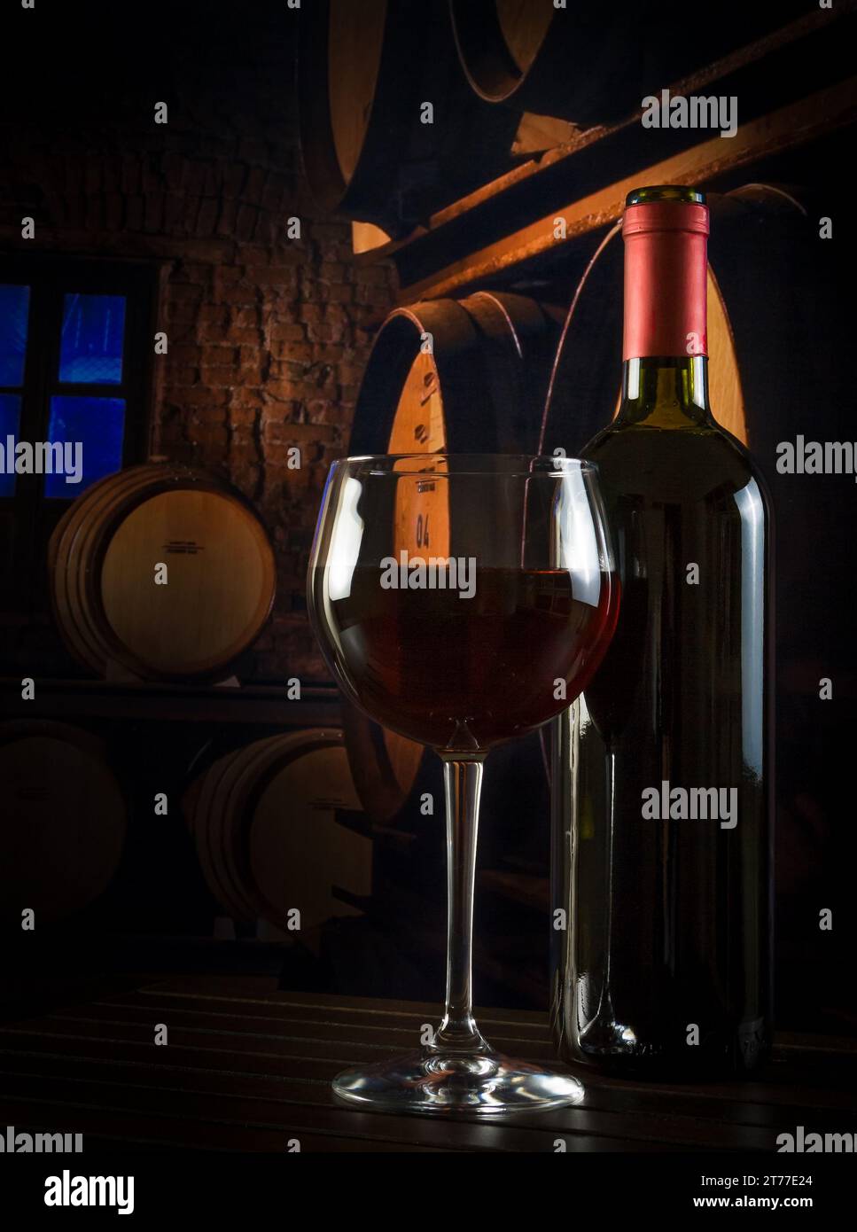 bicchiere di vino vicino alla bottiglia nella vecchia cantina con botti Foto Stock