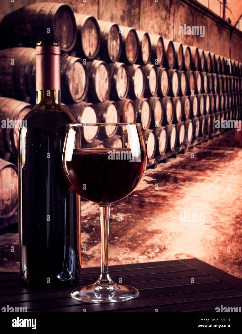 bicchiere di vino rosso vicino alla bottiglia nella vecchia cantina con fondo in botti Foto Stock