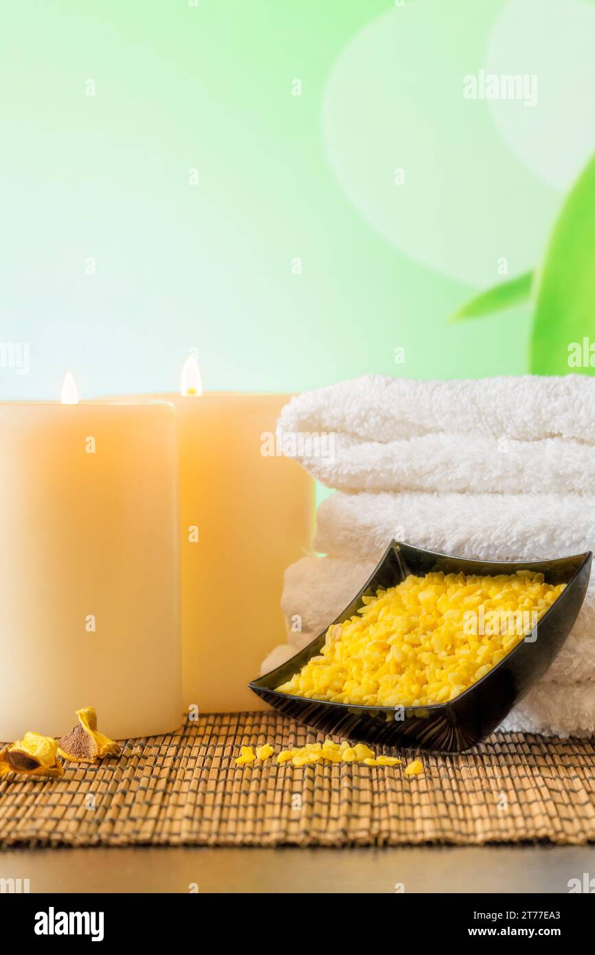 Massaggio Spa con sfondo bordo con asciugamano impilato, candele e sale marino su panno di bambù Foto Stock