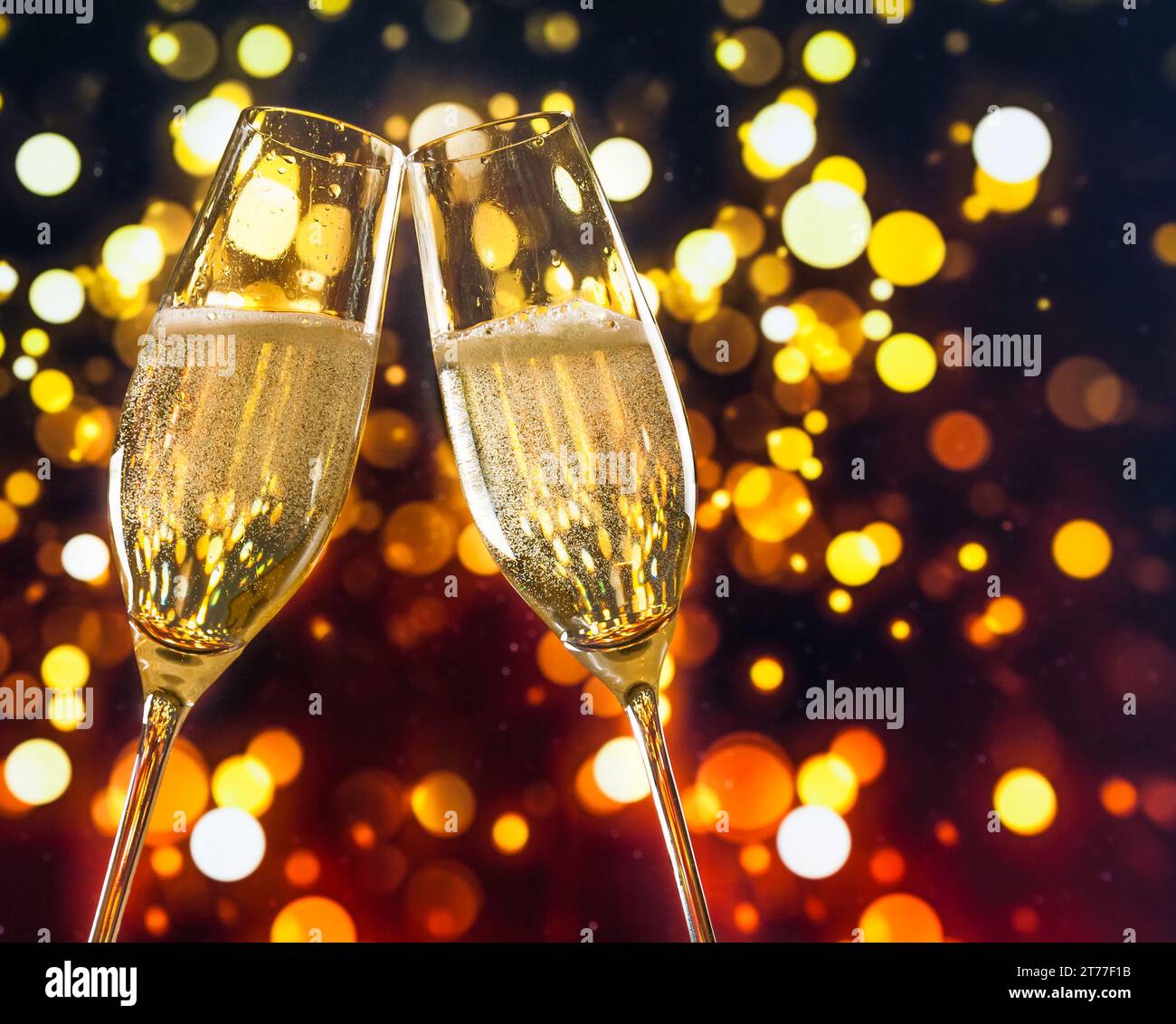 due flauti di champagne con bolle d'oro fanno il tifo su sfondo bokeh chiaro e colorato con spazio per il testo Foto Stock
