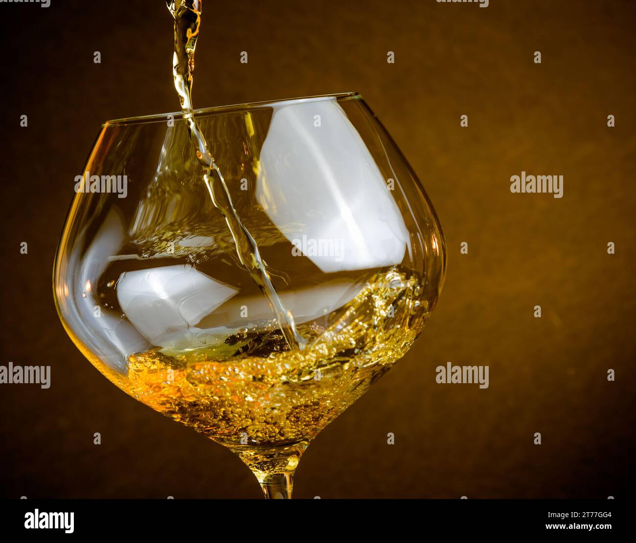 versare vino bianco in un bicchiere su sfondo dorato con spazio per il testo e un'atmosfera calda Foto Stock