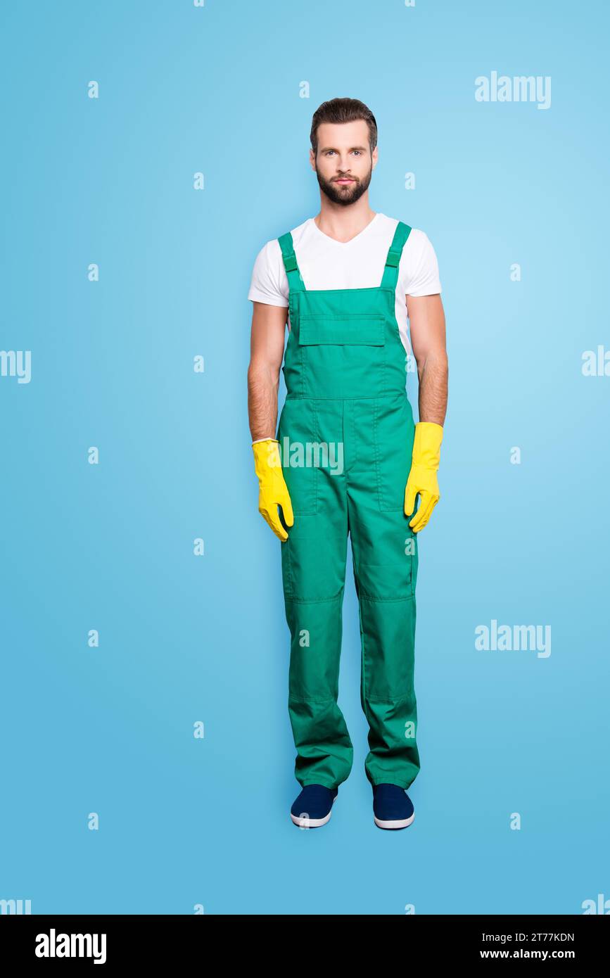 Ritratto integrale a grandezza naturale di bella e attraente bearded governante concentrata con stoppia, acconciatura in uniforme verde, isolato su grigio Foto Stock