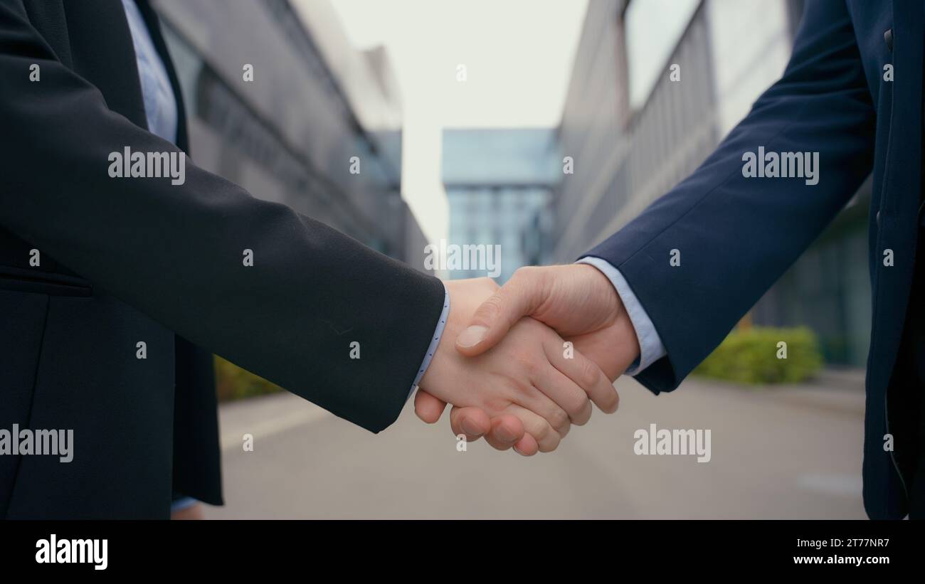 Saluto formale affari stretta di mano città all'aperto edificio di uffici urbano primo piano mani uomo donna handshake accordo di partnership affare di successo femminile Foto Stock