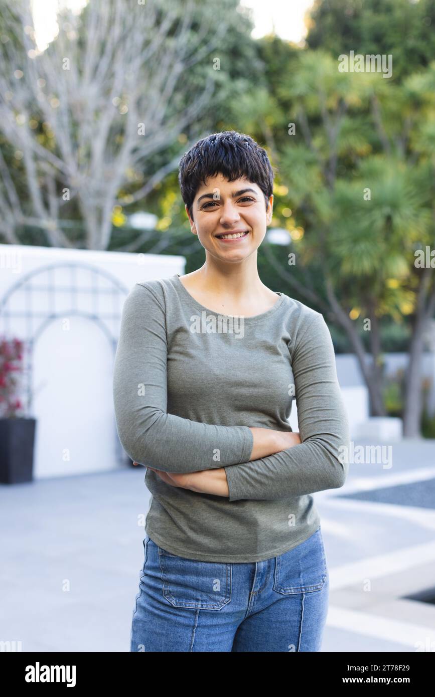 Ritratto di felice donna birazziale con capelli scuri corti in piedi sulla terrazza del giardino sorridente Foto Stock