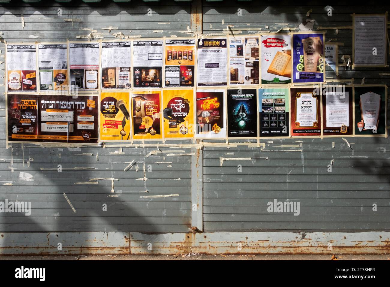 Un muro su Hooper St a Williamsburg con manifesti pubblicitari ed elenchi di eventi che si svolgono principalmente in yiddish. A Brooklyn, New York. Foto Stock