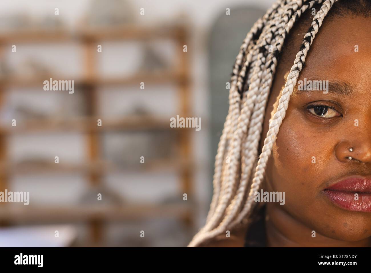 Mezzo volto di una seria ceramista afroamericana con trecce in piedi in uno studio di ceramica Foto Stock