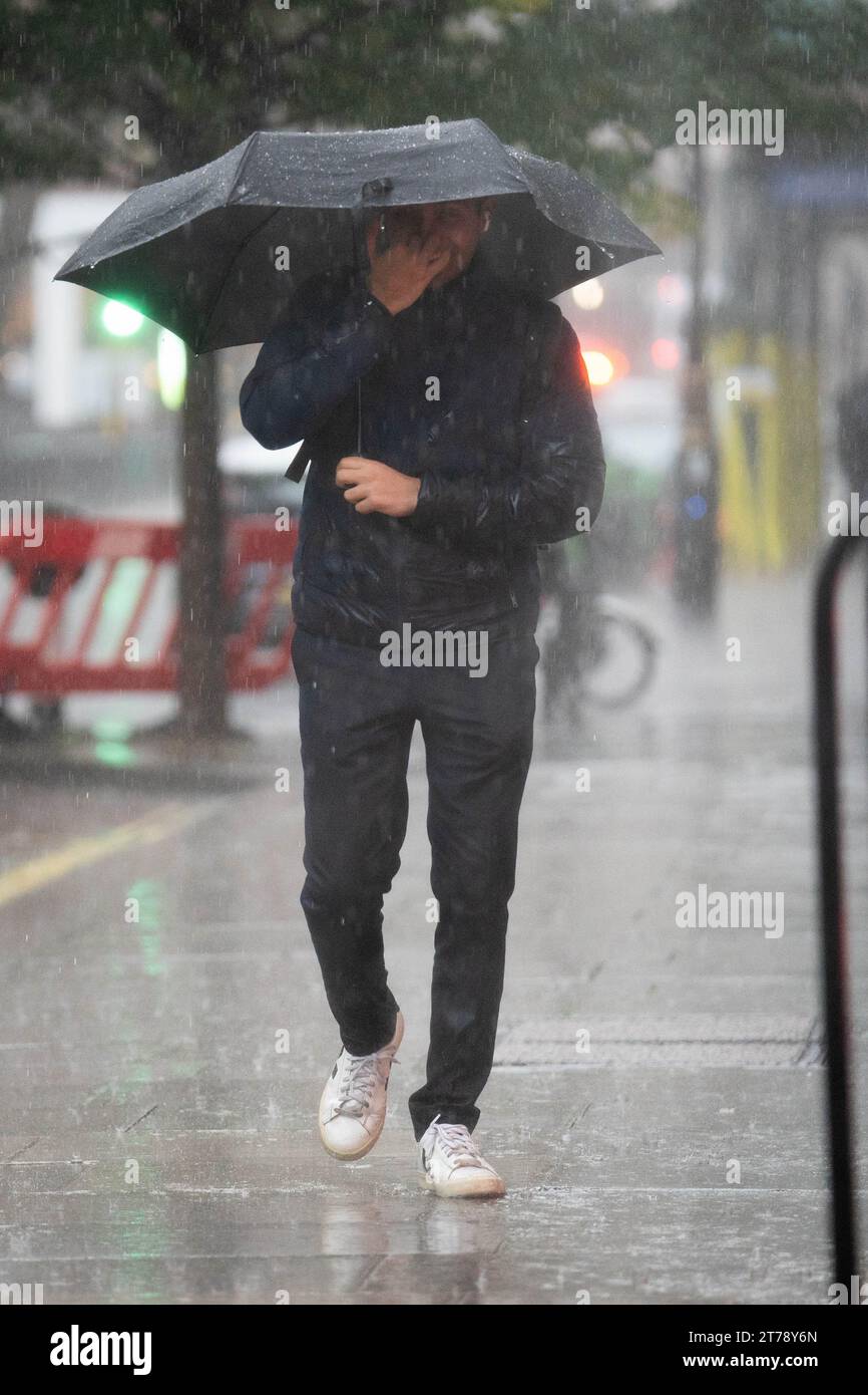La gente cammina sotto la pioggia vicino all'ufficio domestico nel centro di Londra. Una settimana di pioggia potrebbe cadere in poche ore in varie parti del Regno Unito martedì, mentre il clima umido continua a battere il paese. Data immagine: Martedì 14 novembre 2023. Foto Stock