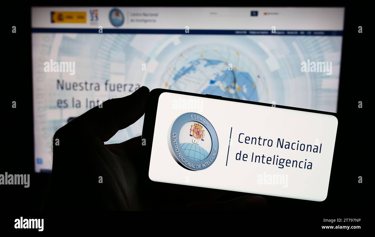 Persona che possiede uno smartphone con il logo dell'agenzia di intelligence Centro Nacional de Inteligencia (CNI) davanti al sito Web. Concentrarsi sul display del telefono. Foto Stock