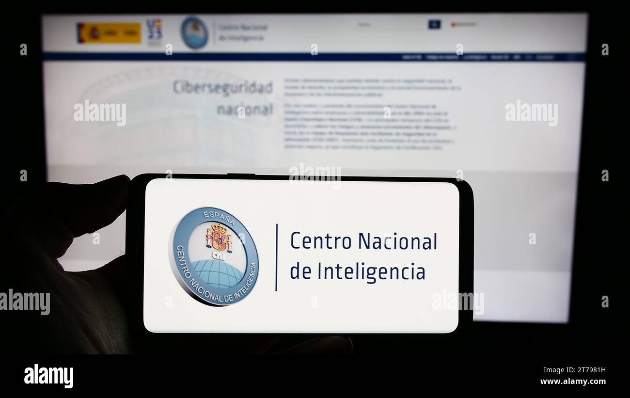 Persona in possesso di un cellulare con il logo dell'agenzia di intelligenza Centro Nacional de Inteligencia (CNI) davanti alla pagina web. Concentrarsi sul display del telefono. Foto Stock