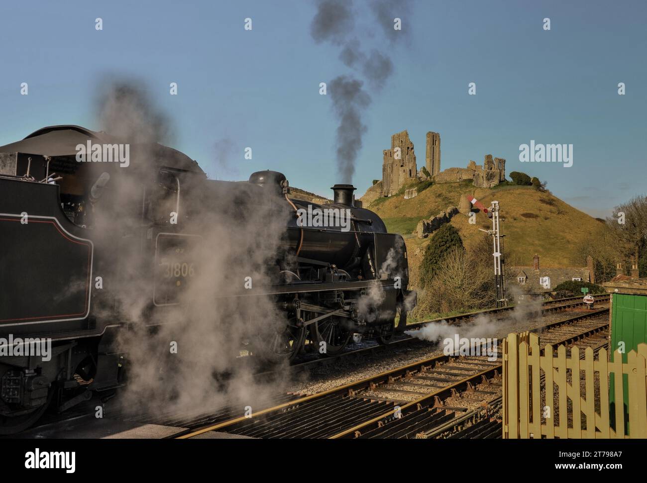 Treno a vapore che passa attraverso la stazione ferroviaria di Corfe con il castello di Corfe Foto Stock