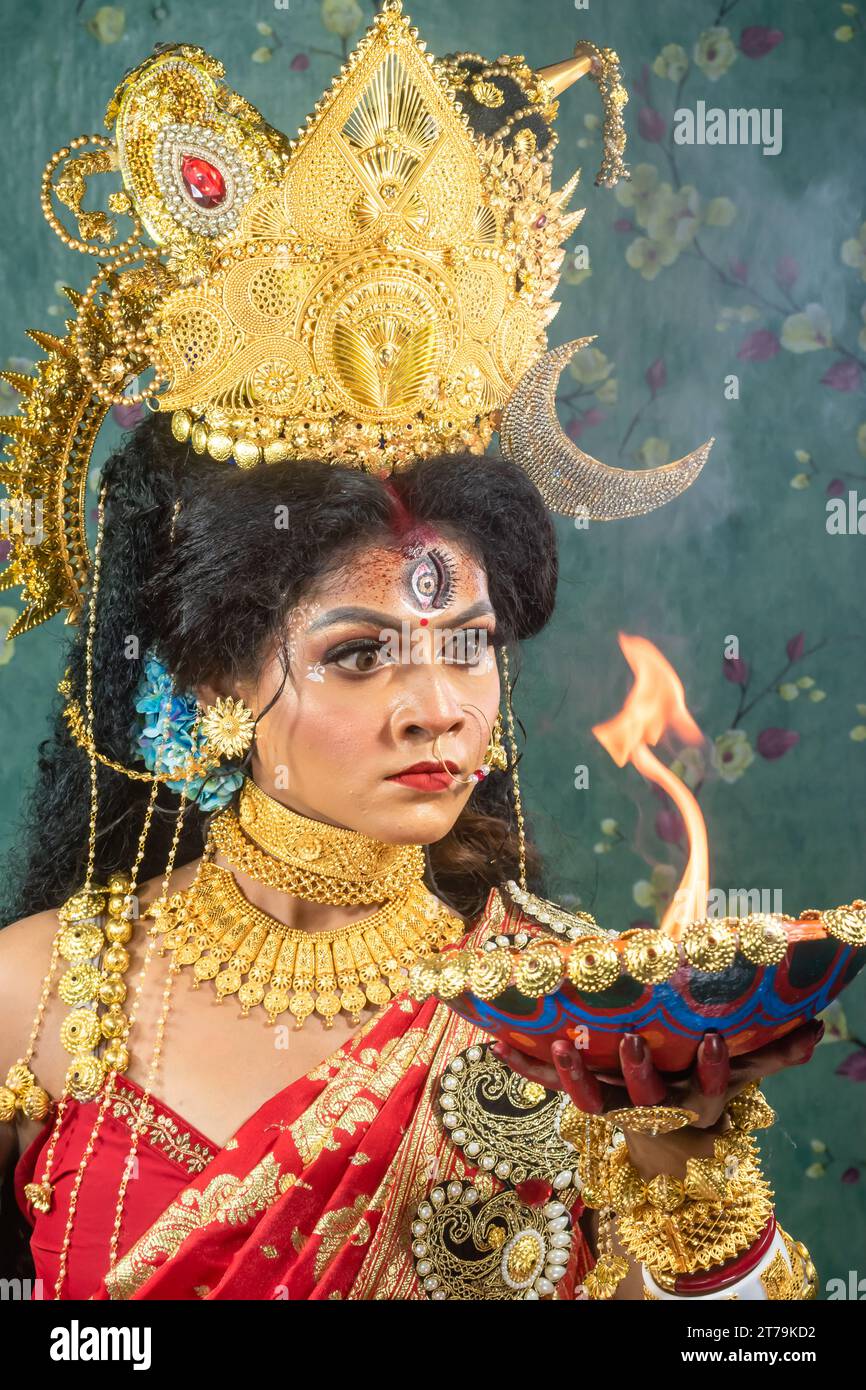 Ritratto della bellissima ragazza indiana di Durga Idol Agomoni Concept foto al coperto che indossa il tradizionale sari indiano, gioielli in oro e braccialetti. Maa Durga. Foto Stock