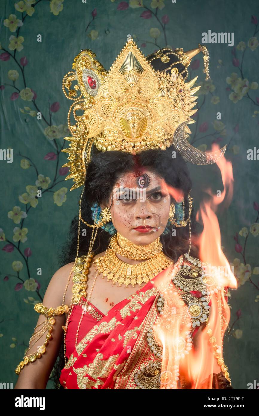 Ritratto della bellissima ragazza indiana di Durga Idol Agomoni Concept foto al coperto che indossa il tradizionale sari indiano, gioielli in oro e braccialetti. Maa Durga. Foto Stock