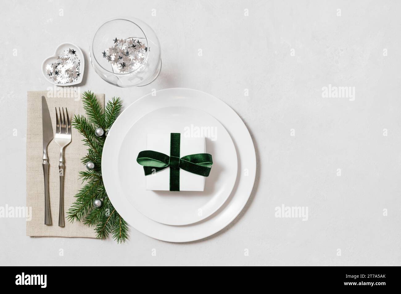 Impostazione del tavolo di Natale su sfondo bianco con spazio per la copia. Regalo di Capodanno in un piatto. Servizio natalizio con decorazioni natalizie. Vista dall'alto, base piatta. Foto Stock