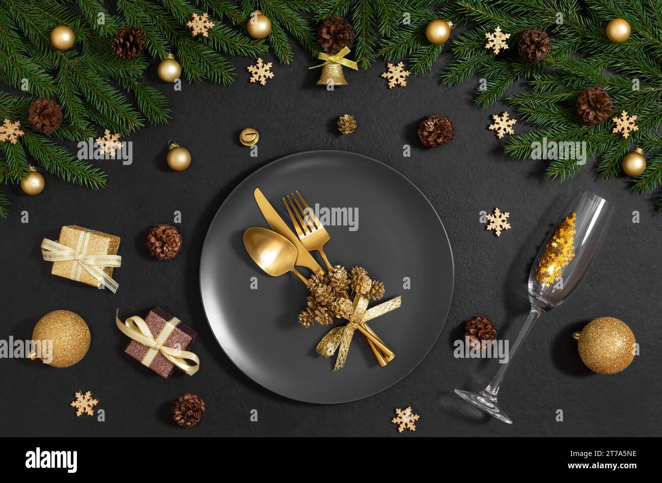 Tavolo nero con decorazioni natalizie e posate dorate. La vigilia di Capodanno è su sfondo nero. Cena di Natale. Vista dall'alto, base piatta. Foto Stock