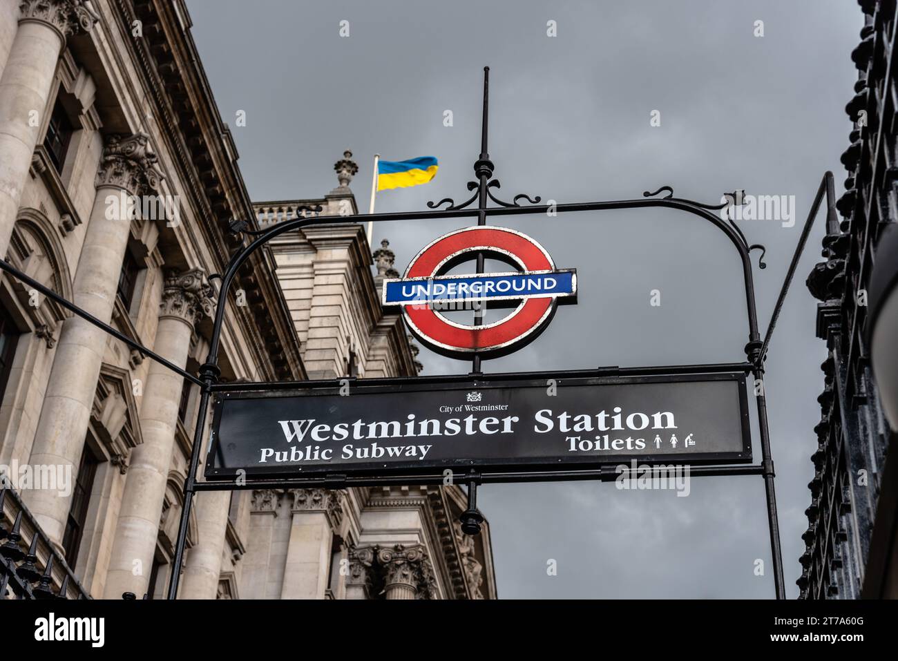 Londra, Regno Unito - 26 agosto 2023: Vista ravvicinata del cartello della metropolitana di Londra nella stazione di Westminster contro il cielo nuvoloso e la bandiera ukraniana Foto Stock