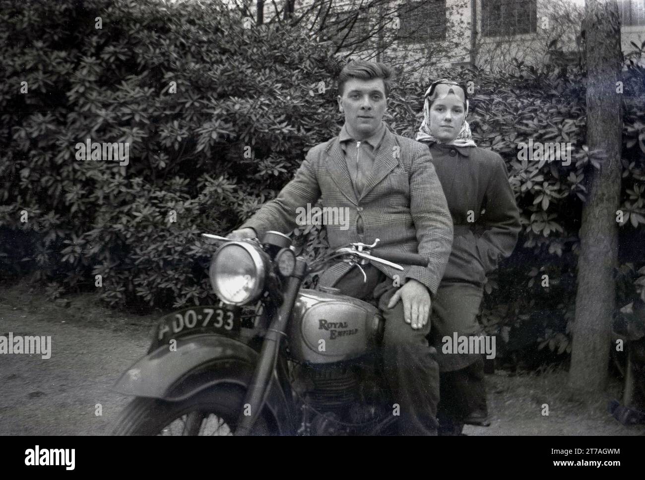 Anni '1950, un giovane uomo e una giovane donna, con gli occhiali facciali, all'inizio degli anni '20, seduti su una moto Royal Enfield dell'epoca, Oldham, Manchester, Inghilterra, Regno Unito. Le motociclette Royal Enfield prodotte dalla British furono prodotte a Redditch, Worcestershire, dalla Enfield Cycle Company, la prima costruita nel 1901. Foto Stock