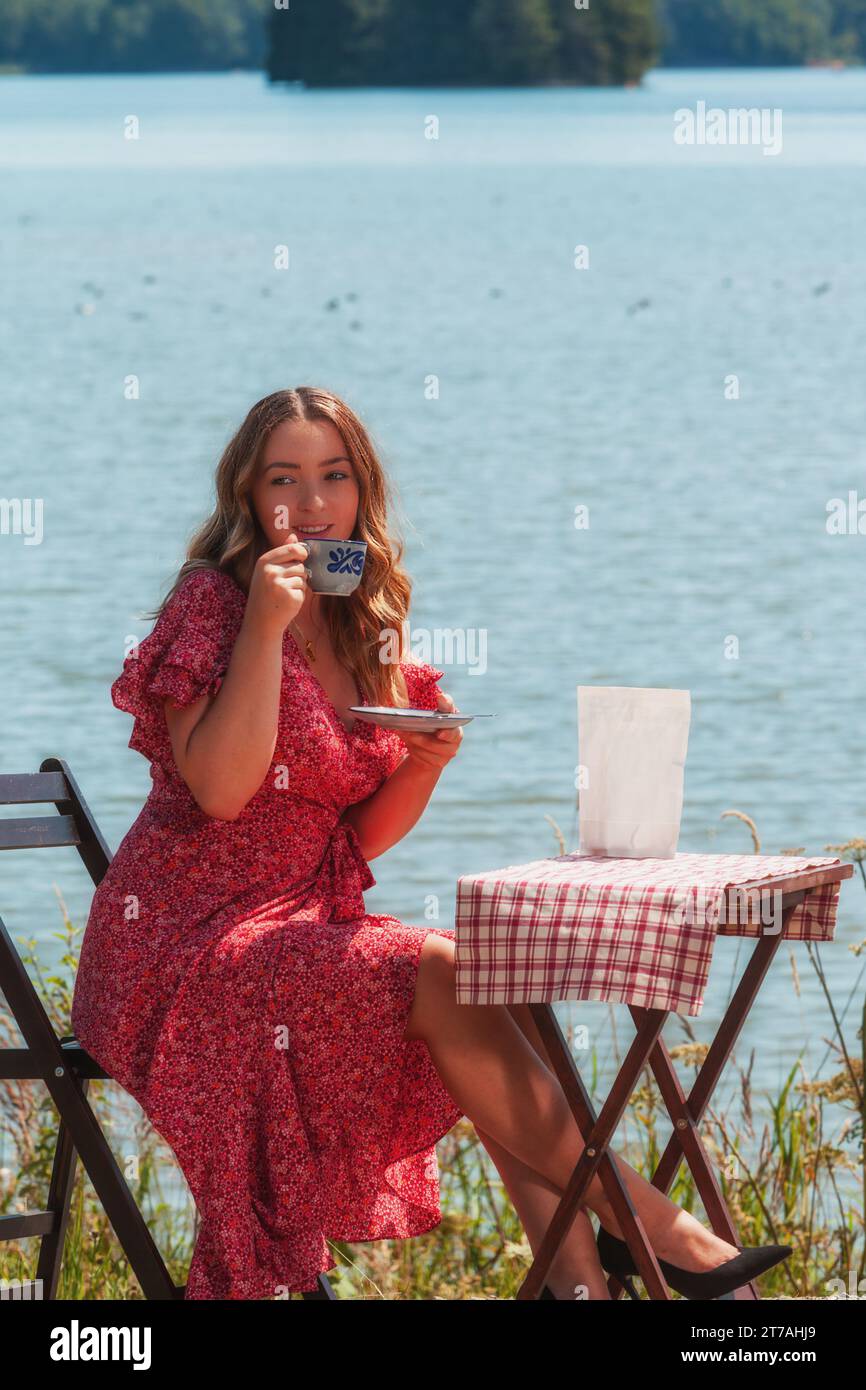 Ritratto di una donna sorridente con una tazza di caffè in mano. Foto Stock