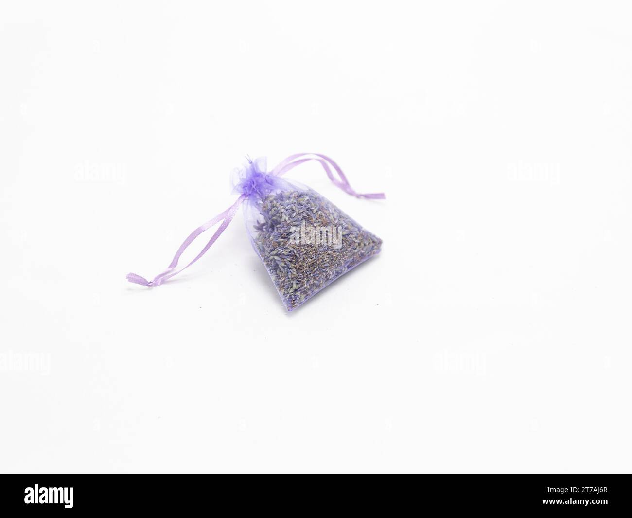 Una piccola bustina viola piena di lavanda secca su sfondo bianco. Foto Stock