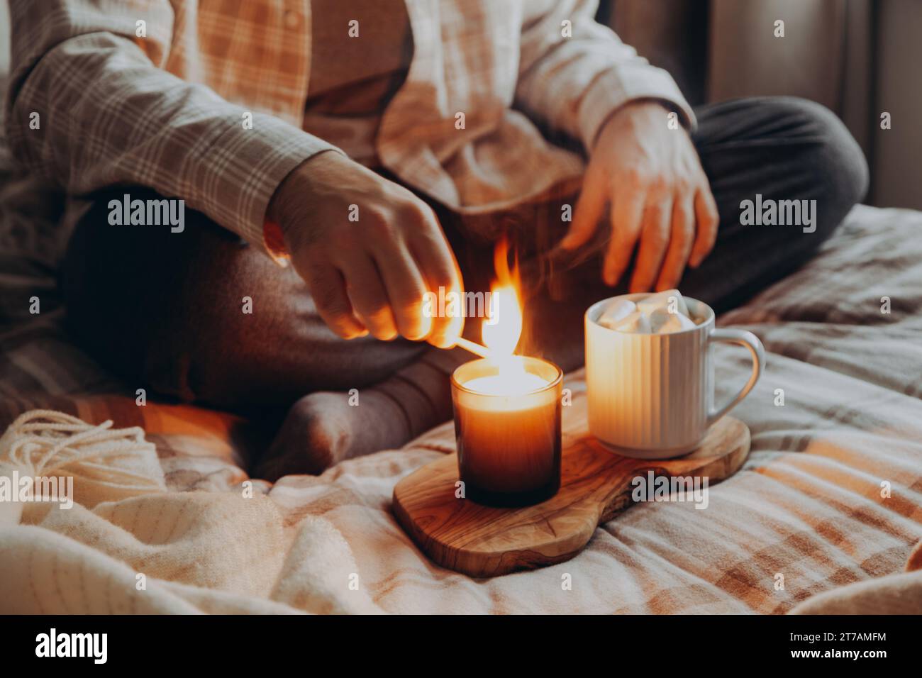 un uomo caucasico che si rilassa a casa, accendendo candela, bevendo caffè a letto Foto Stock