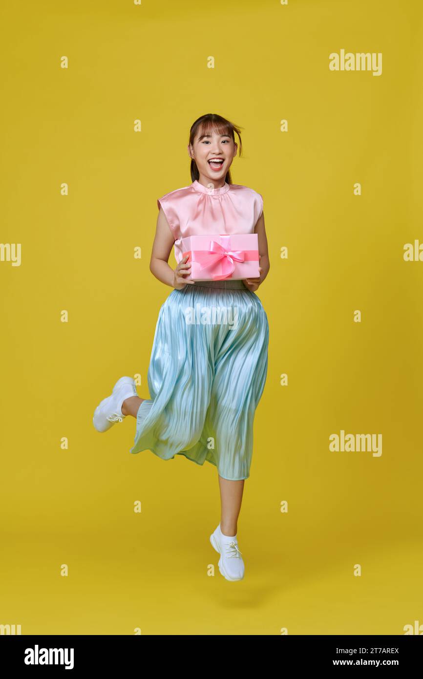 Foto di profilo a grandezza naturale di Pretty Lady Jump con presente isolato su sfondo giallo Foto Stock