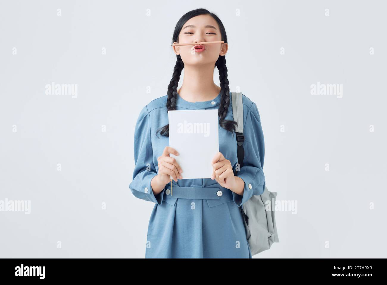 Ritratto di una divertente studentessa che tiene la matita tra naso e labbra come baffi Foto Stock