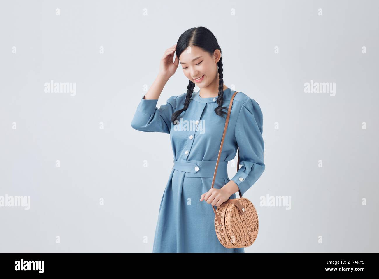 Bellissima giovane donna sorridente con abito in denim, borsa isolata su sfondo bianco Foto Stock