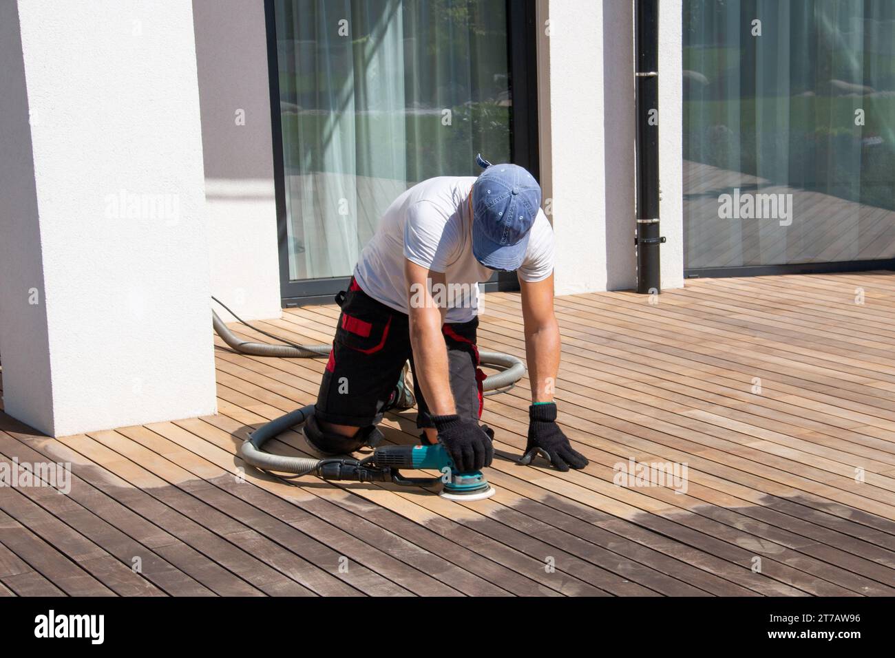 Carteggiatrice per costruttori di ponti che levigano pannelli di legno ipe con la levigatrice orbitale professionale sul ponte esterno della terrazza Foto Stock