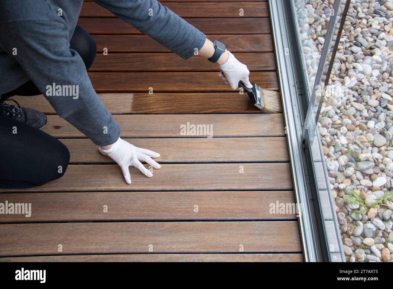 Sigillatura e verniciatura di pavimenti in legno, tenendo a mano una spazzola applicando uno strato protettivo trasparente Foto Stock