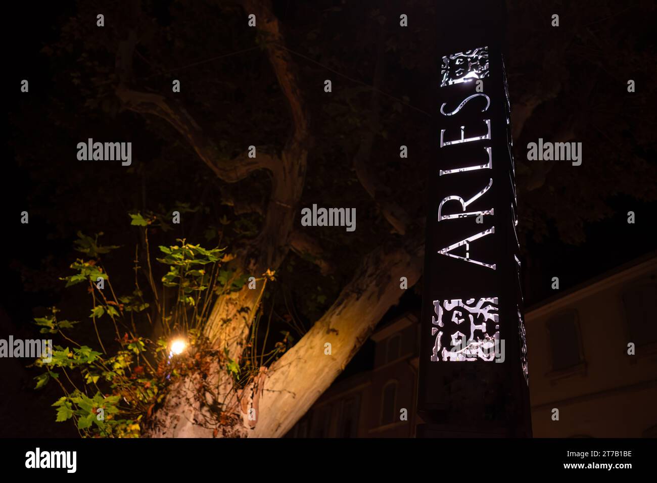 Arles, Francia - 1° ottobre 2023: Colonna metallica illuminata in strada con il nome della città di Arles francese di notte Foto Stock