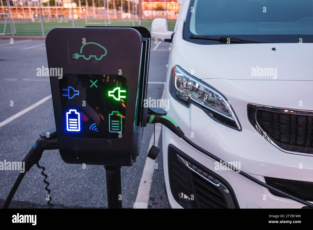 Stazione di ricarica per auto elettriche e ricarica di un'auto in un parcheggio pubblico con elettricità Foto Stock