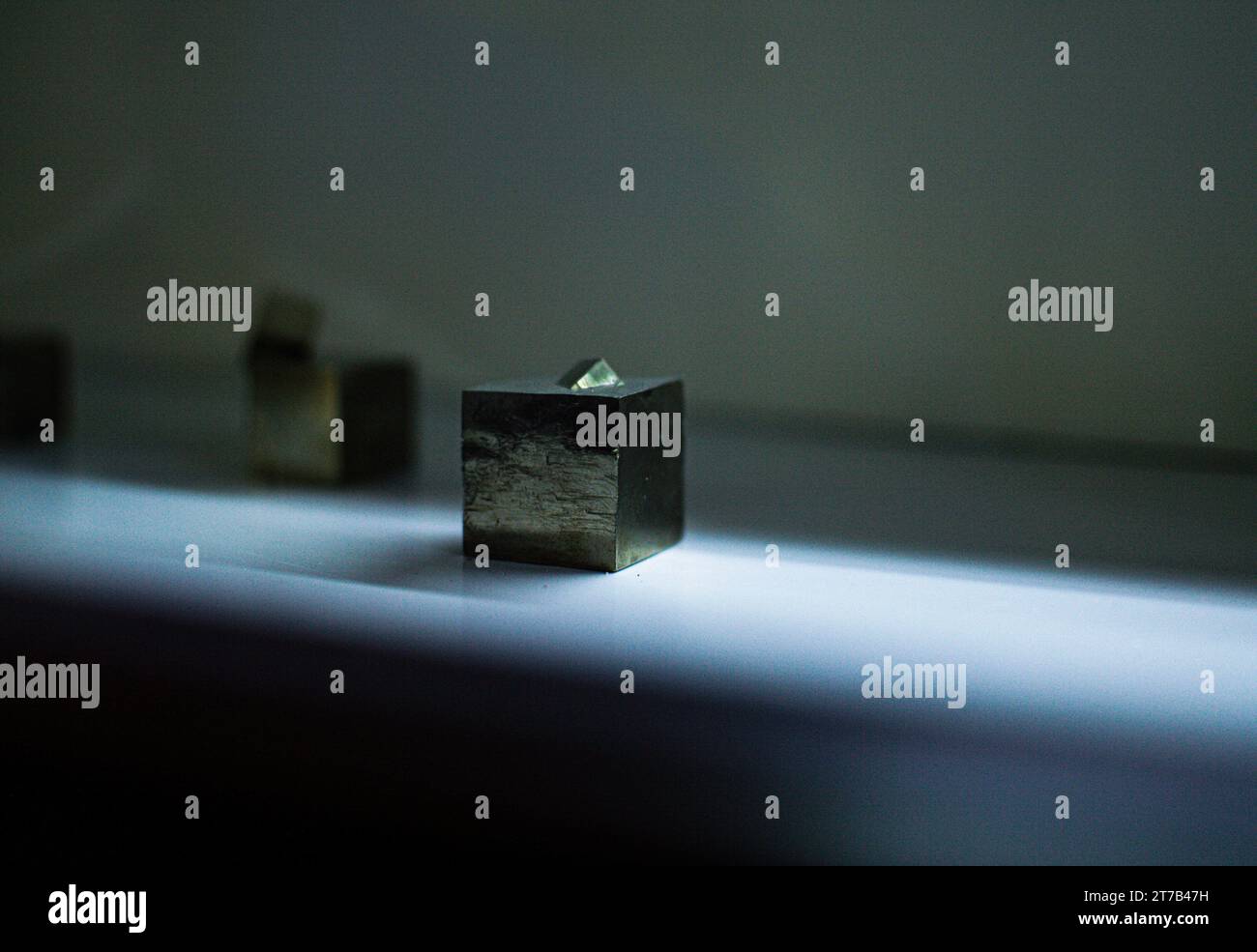 Un oggetto in argento metallizzato si trova su un piano di lavoro, illuminato da una fonte di luce sottostante Foto Stock