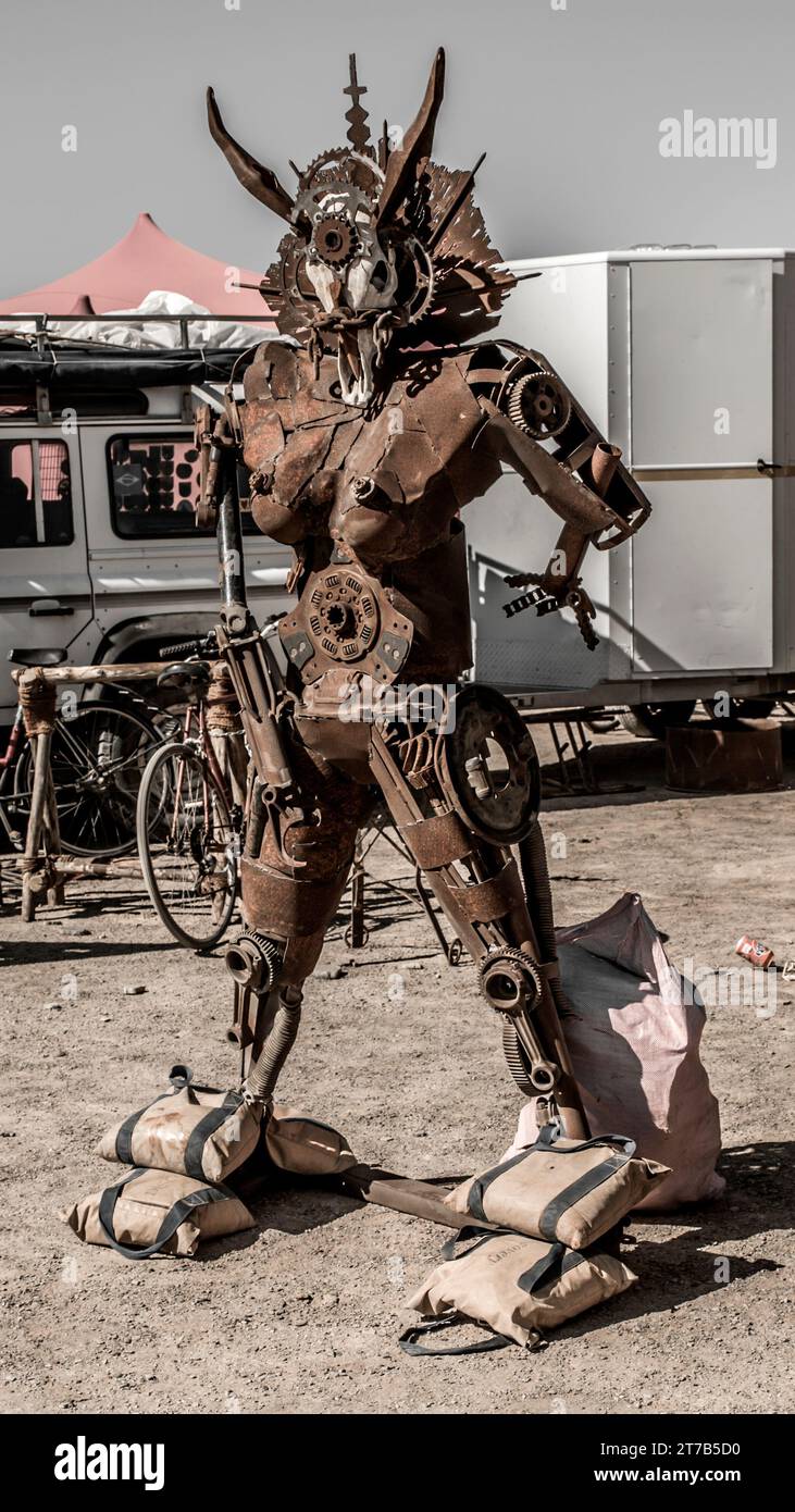 Una figura robotica extraterrestre in piedi vicino a una borsa piena di oggetti vari Foto Stock