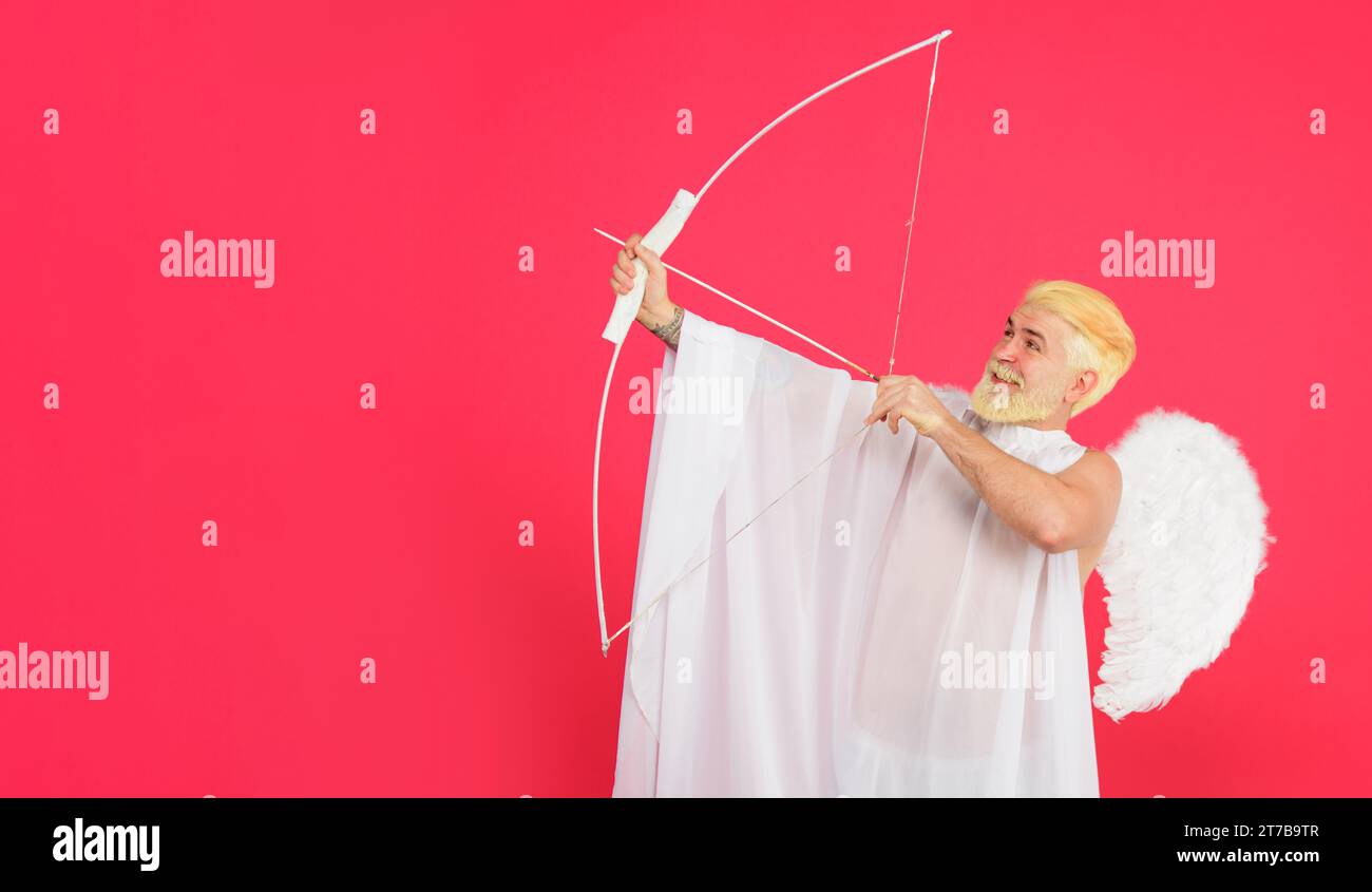 San Valentino. Uomo barbato sorridente con ali d'angelo bianche che sparano freccia d'amore. San Valentino cupido con arco e freccia. Angelo maschio con arco e freccia Foto Stock